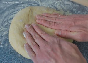 Die mit Käse gefüllte Teigkugel für georgische Chatschapuri vorsichtig mit den Händen plattdrücken